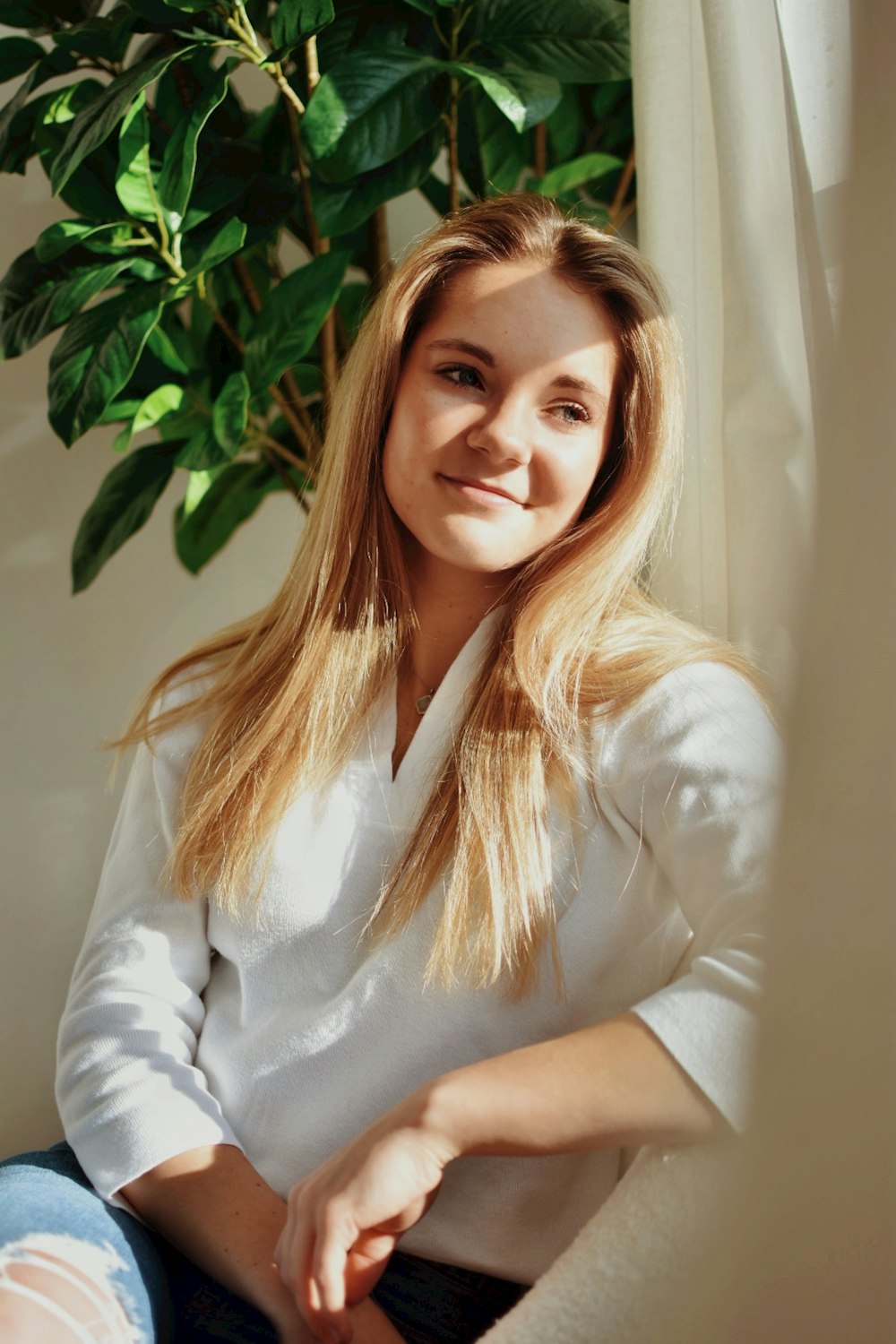 a woman sitting in front of a potted plant