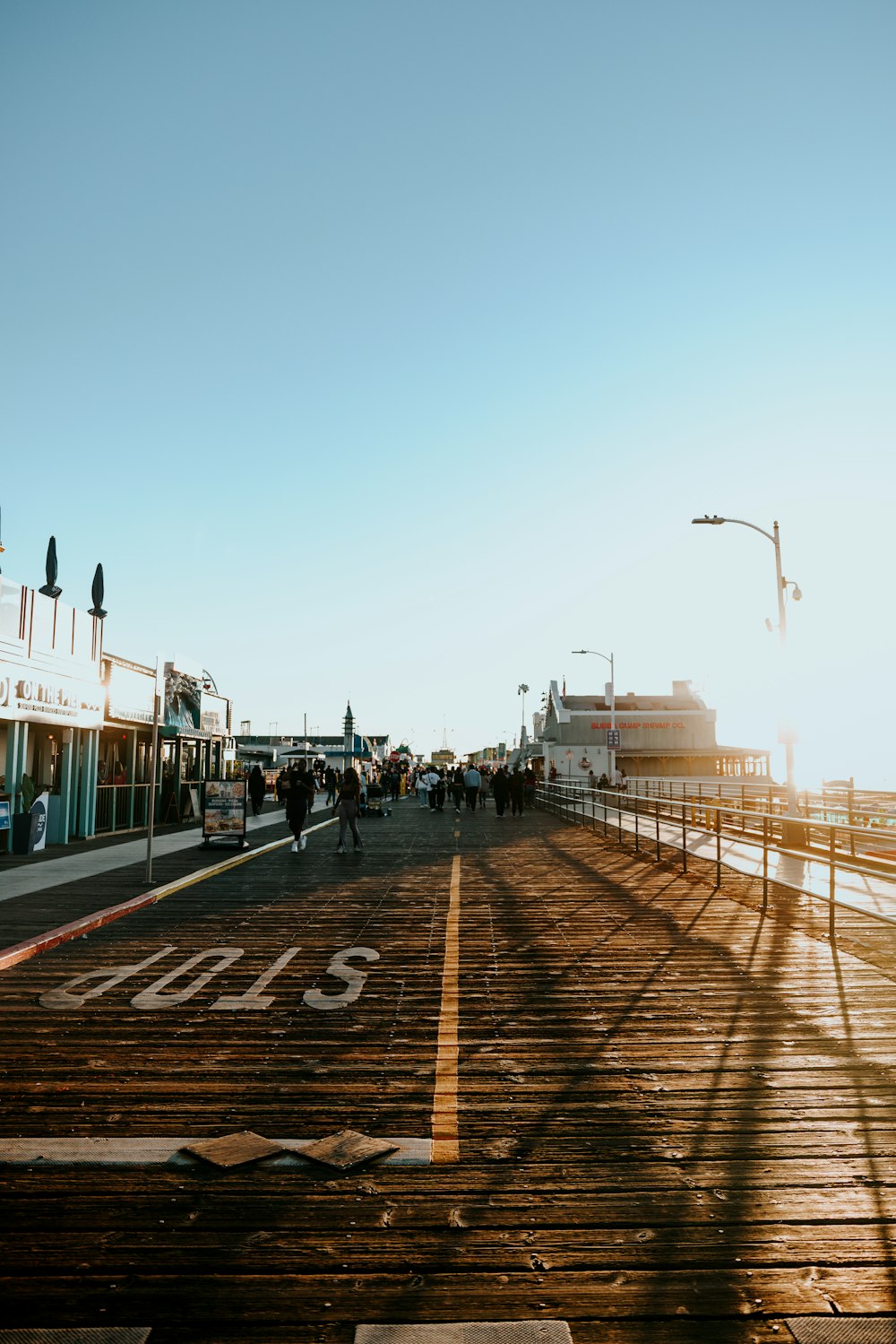 a group of people walking on a boardwalk next to the ocean