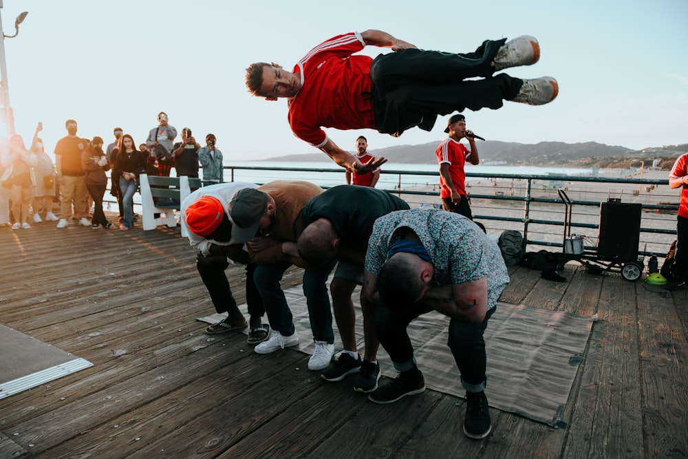 a group of men standing on top of a wooden pier