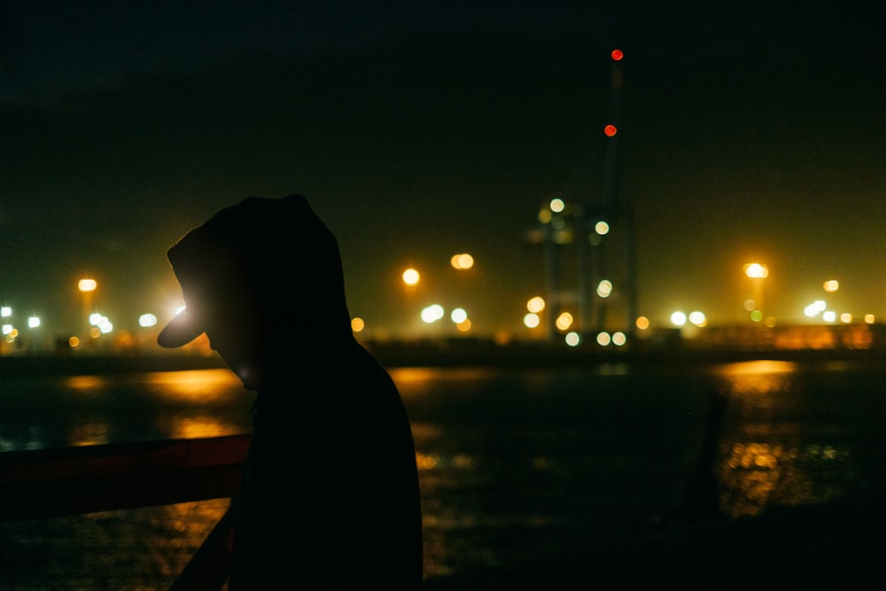 a person standing in front of a body of water at night