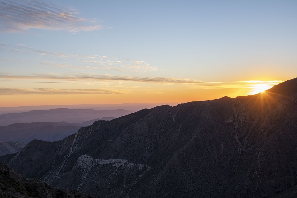 the sun is setting over a mountain range