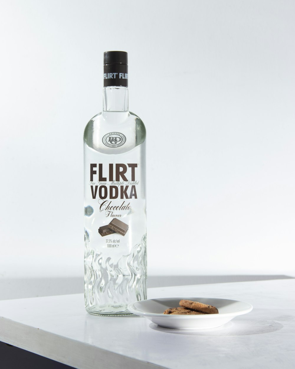 a bottle of vodka next to a plate of cookies