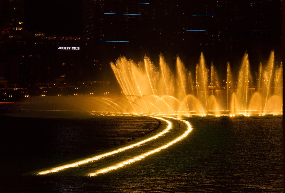 a large fountain of water is lit up at night