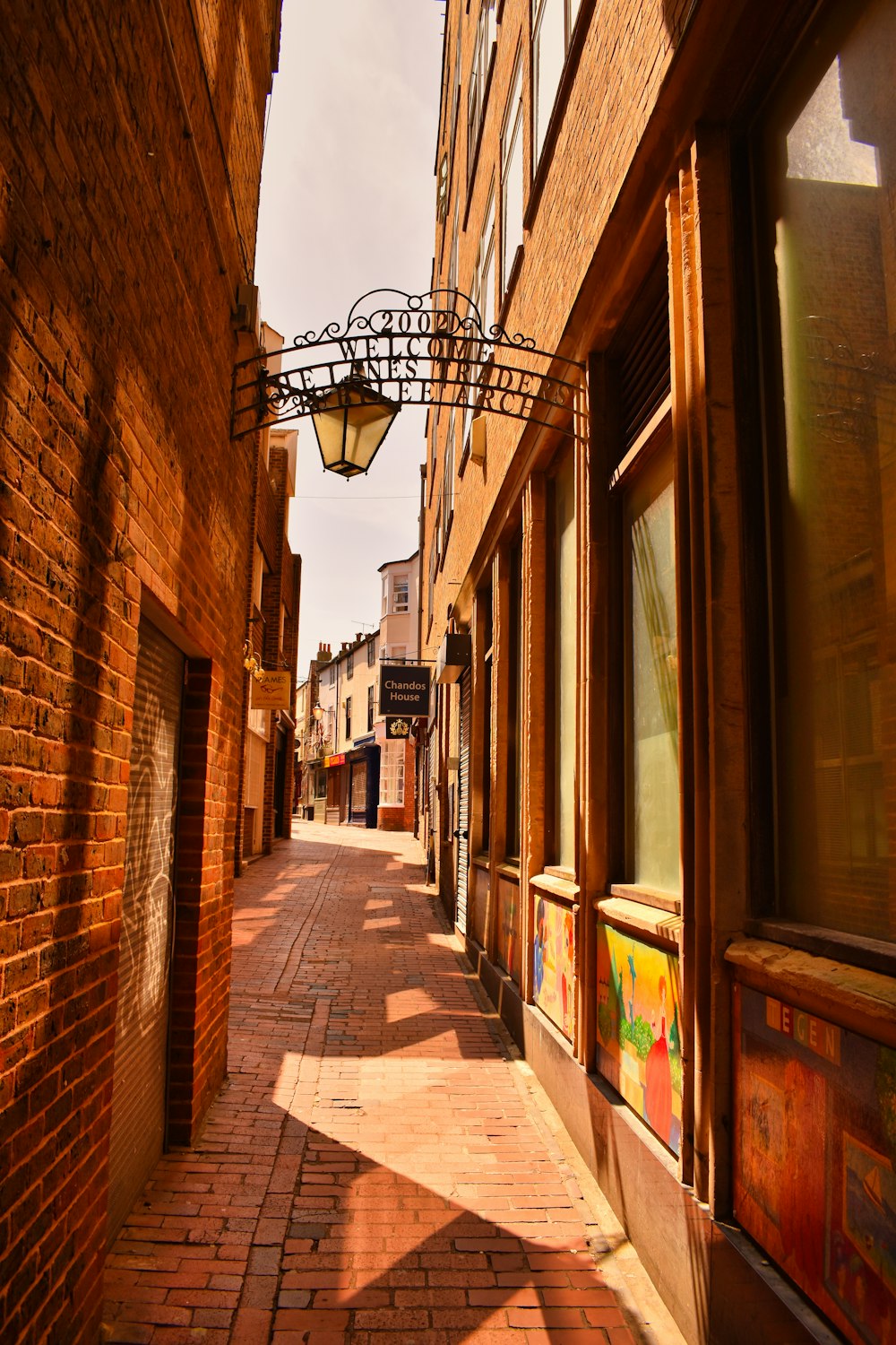 a brick street with a light hanging from the side of it