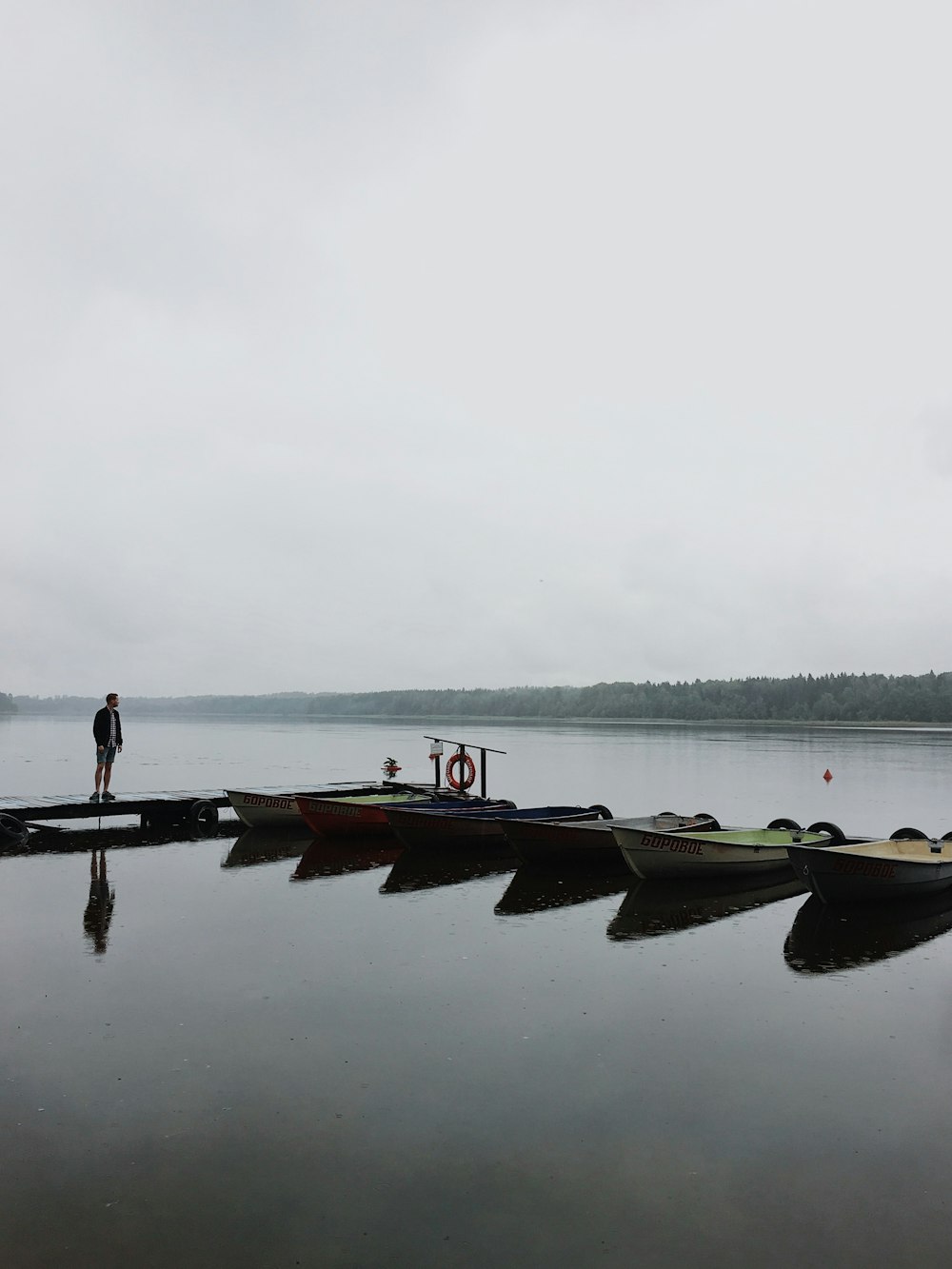 a man standing on a dock next to a row of boats