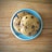 Two chocolate chip cookies are placed on a light blue ceramic plate, which rests on a wooden surface. The cookies have a golden brown appearance and are generously studded with chocolate chips.