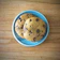 Close-up of a golden, freshly baked American cookie with visible chocolate chunks on a minimalist white plate.