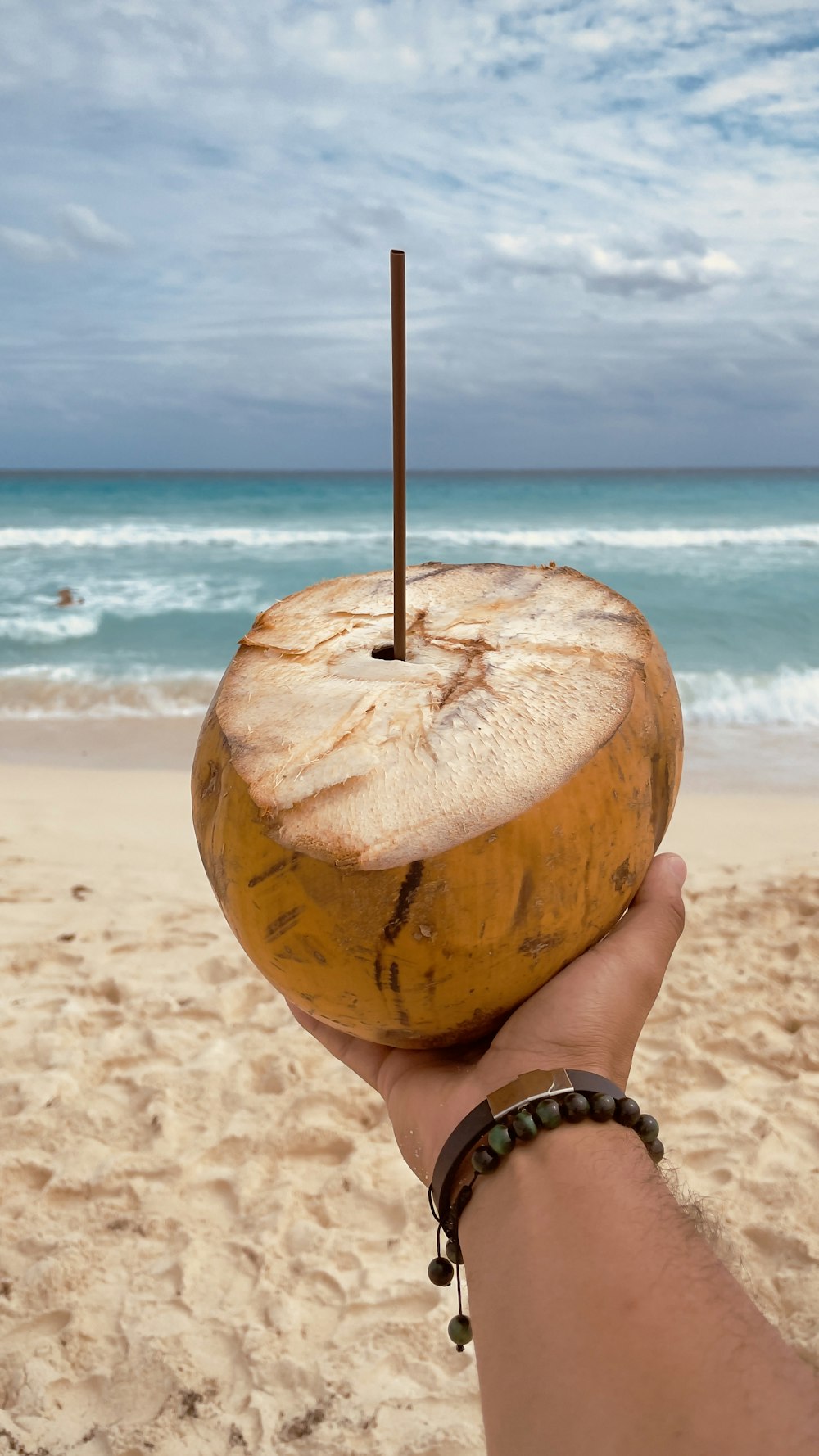 a person holding a coconut on a beach