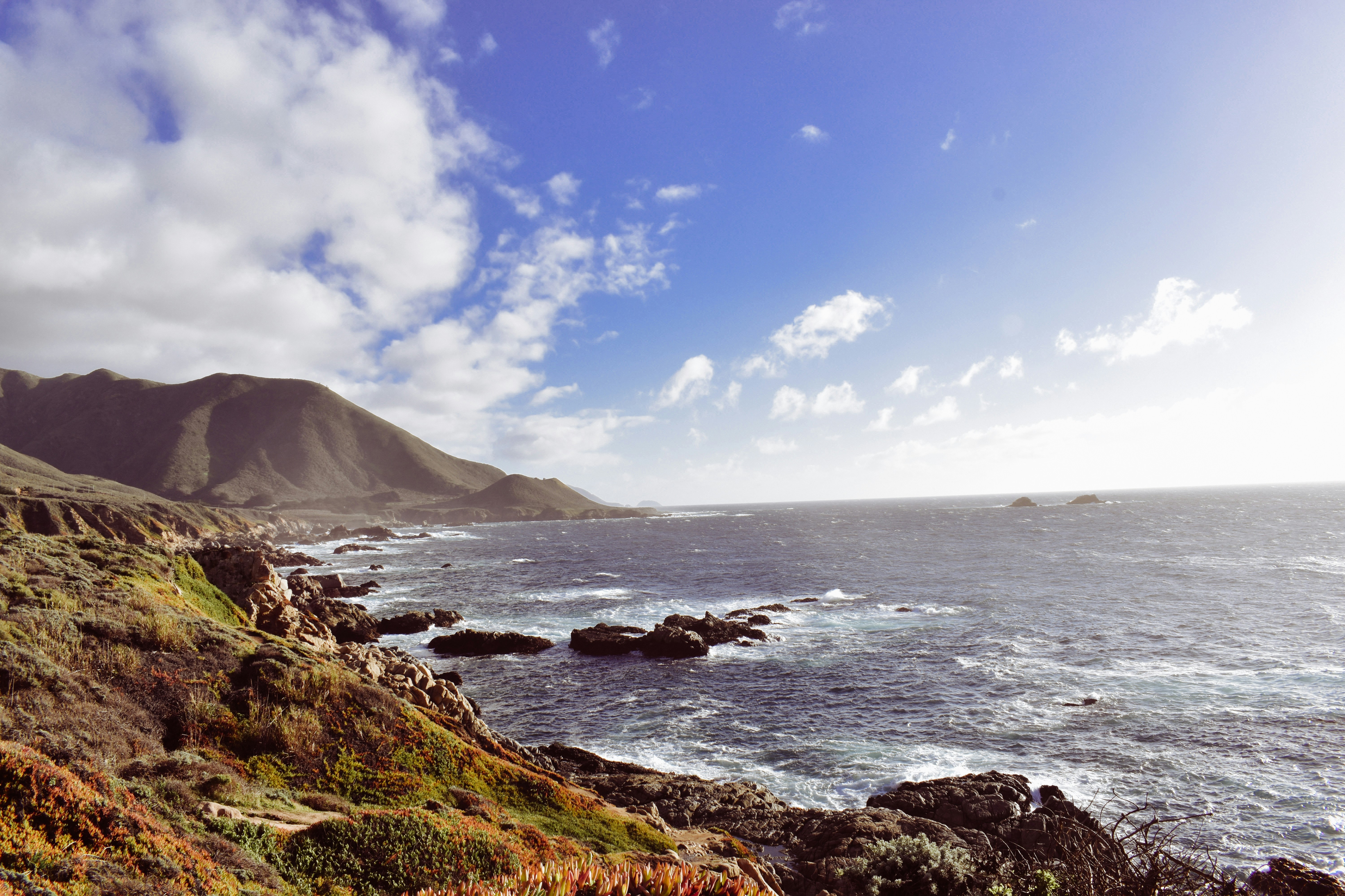 a scenic view of the ocean with a mountain in the background
