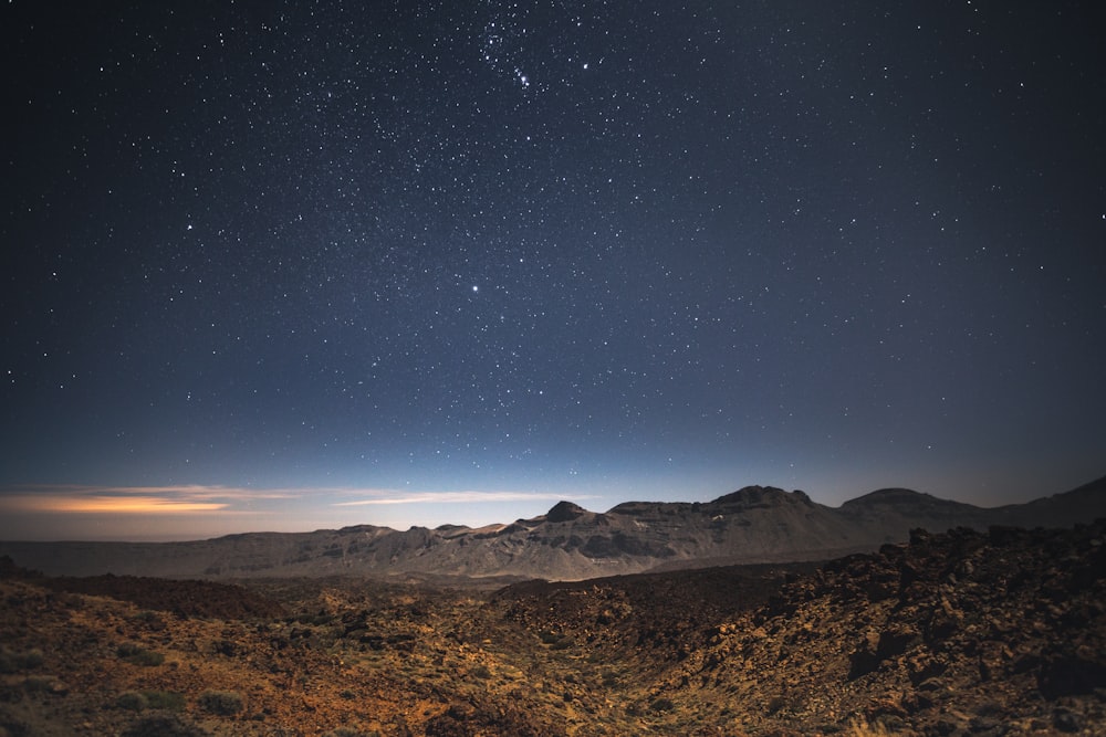 the night sky over a mountain range with stars in the sky