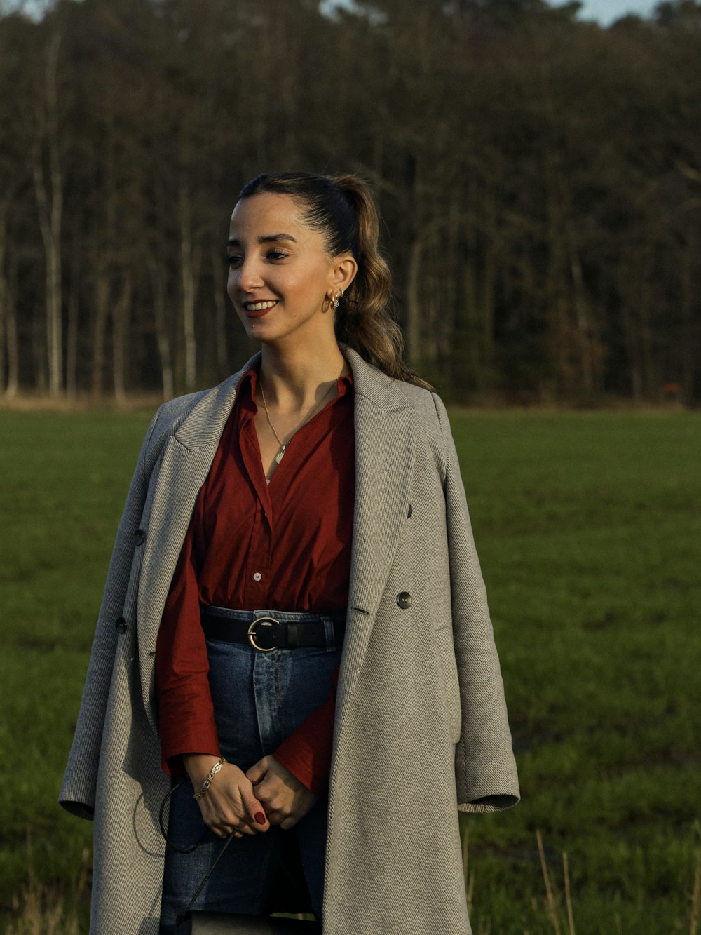 a woman standing in a field with a coat over her shoulders