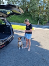 A cheerful pet owner handing over a leash while a dung gone truck waits in the background.