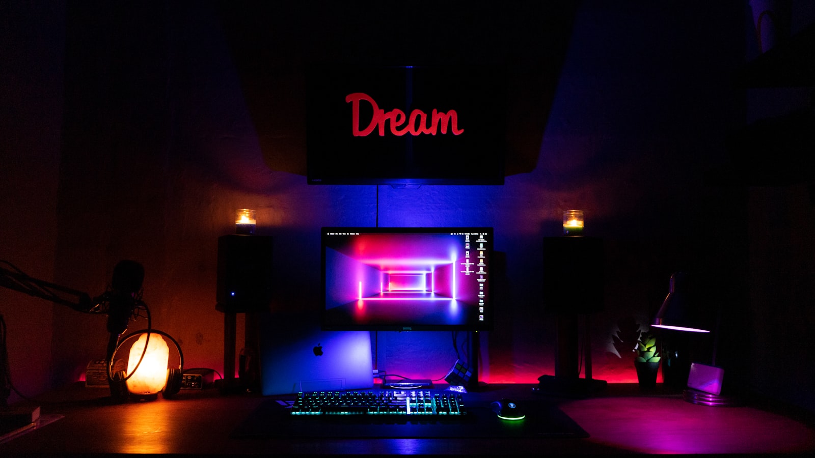A dark desk setup lit by neon with a monitor and keyboard