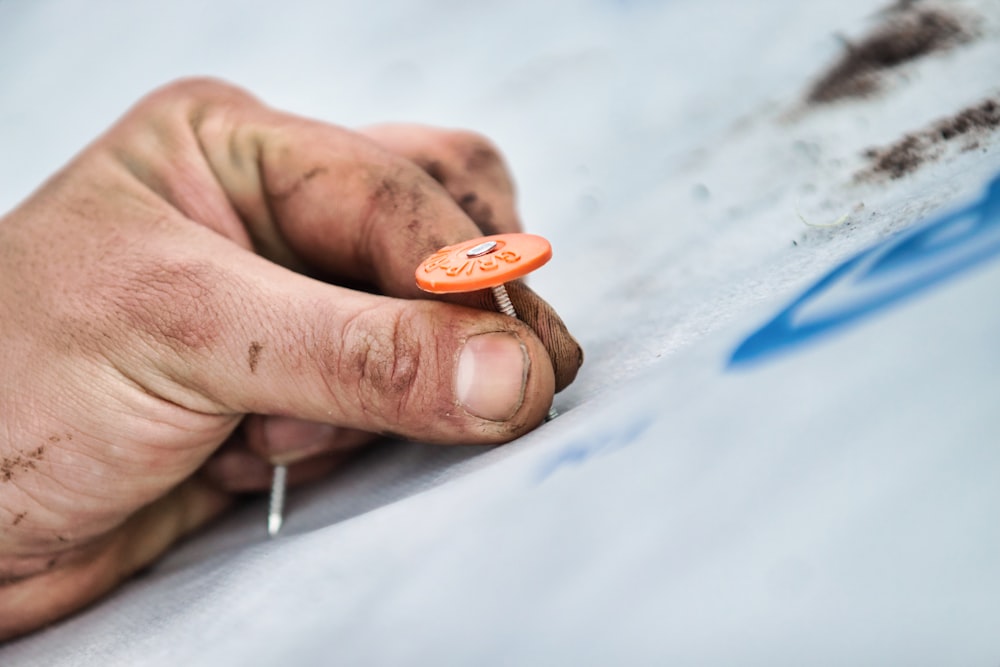 a person holding a small orange button in their left hand