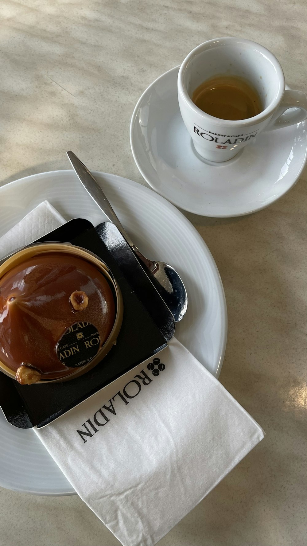 a white plate topped with a piece of cake next to a cup of coffee