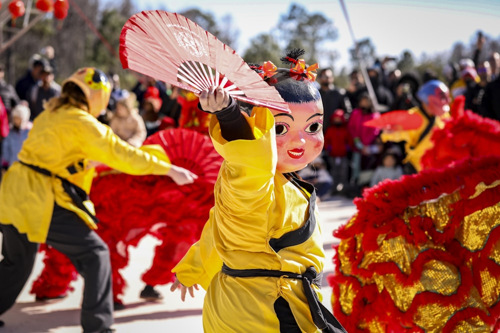 a woman in a yellow dress holding a pink fan