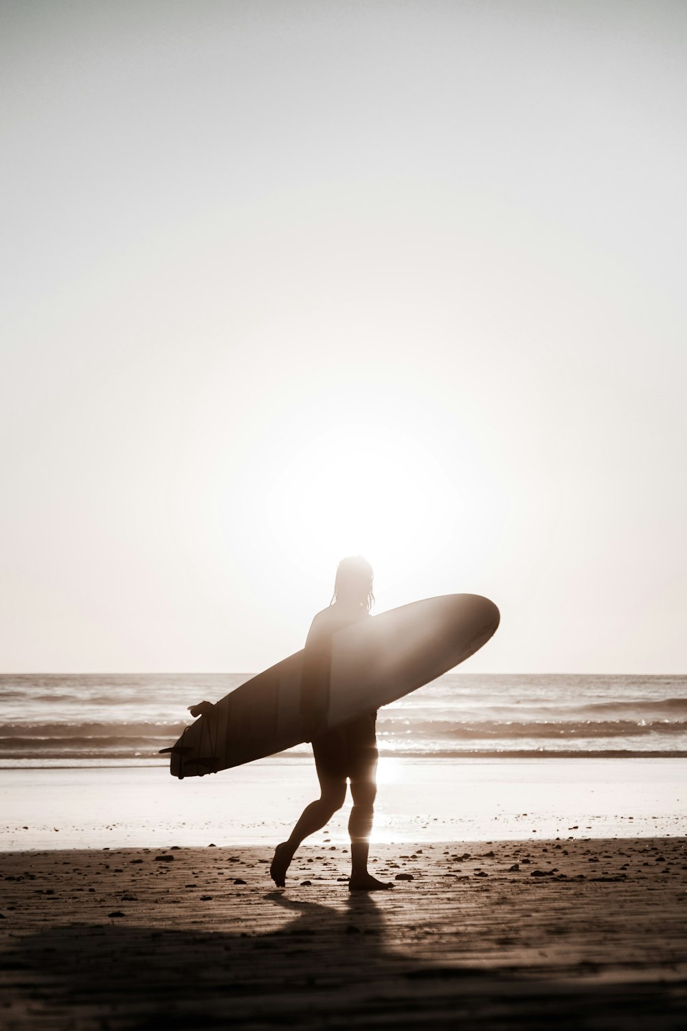 a person walking on a beach with a surfboard