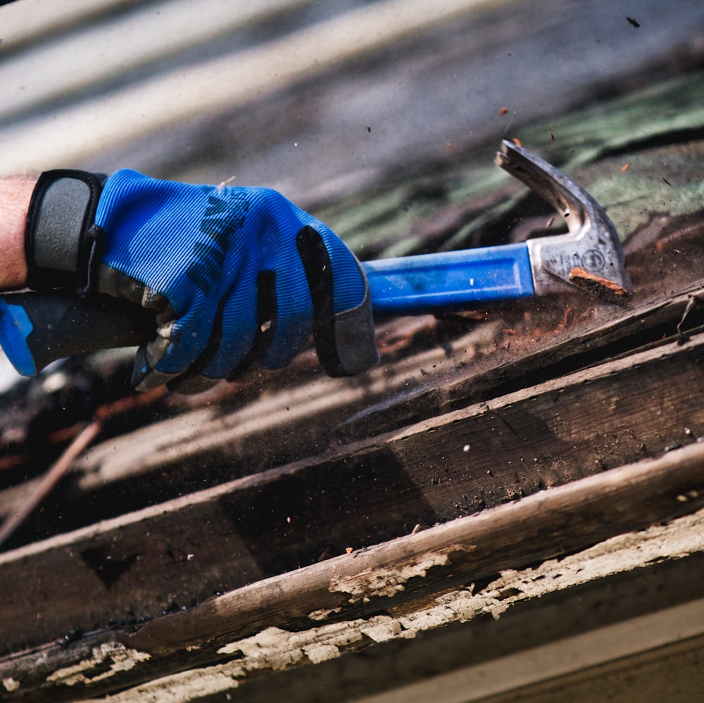 eine Person, die blaue Handschuhe trägt und einen Hammer hält