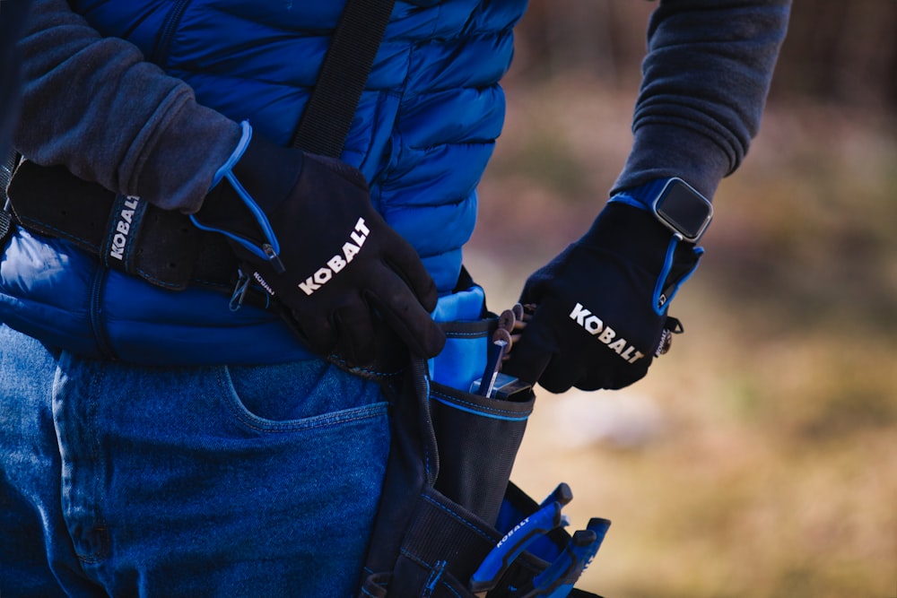 a man in a blue jacket holding a pair of gloves