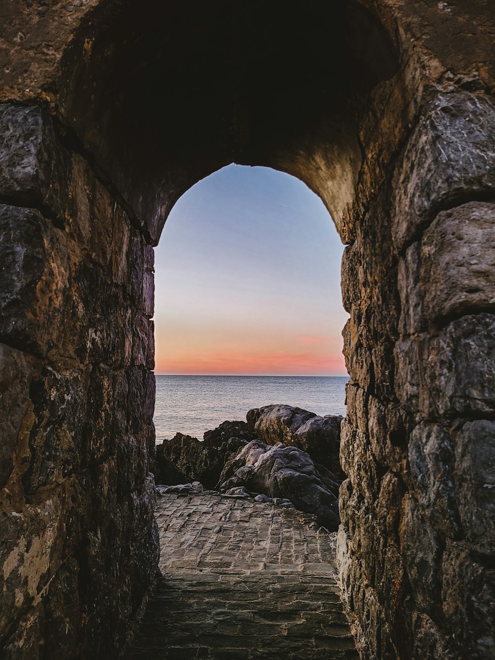 a view of the ocean through a stone archway