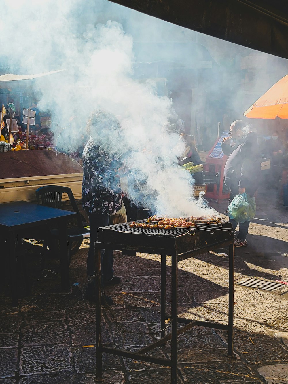 a man cooking food on a grill with smoke coming out of it