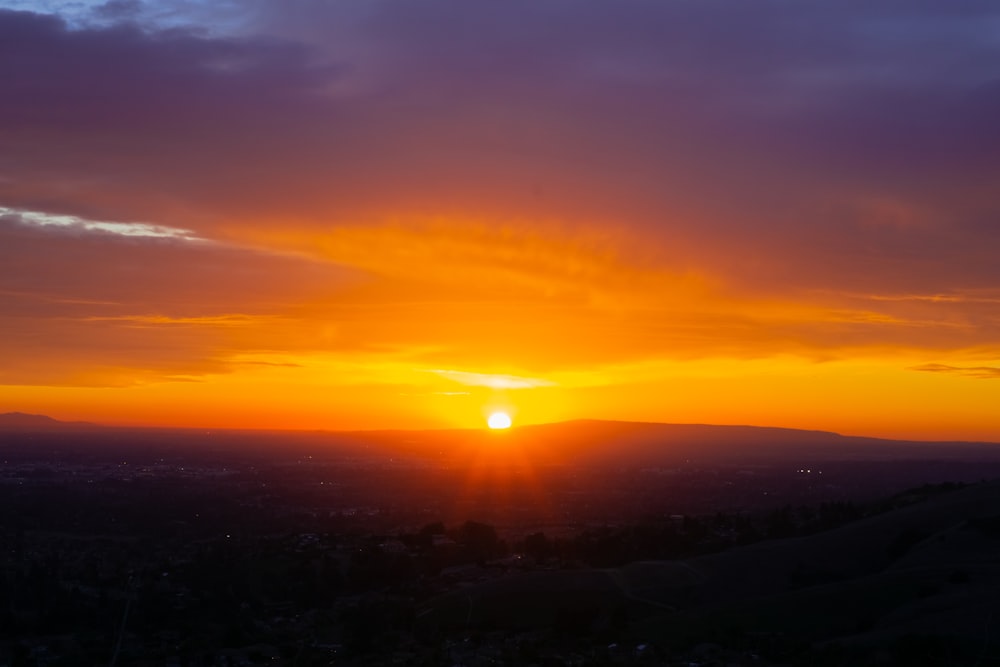 the sun is setting over a valley with mountains in the background