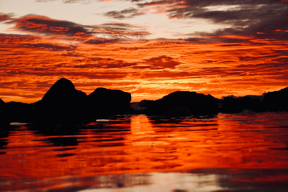 a red sky with clouds reflected in the water