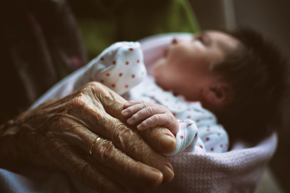 a baby sleeping in a blanket next to an older woman