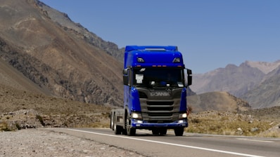 a blue semi truck driving down a mountain road