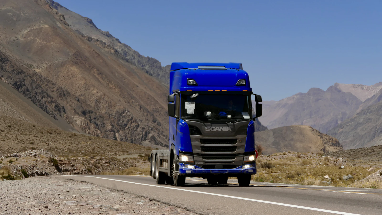 A blue semi truck on a winding mountain road