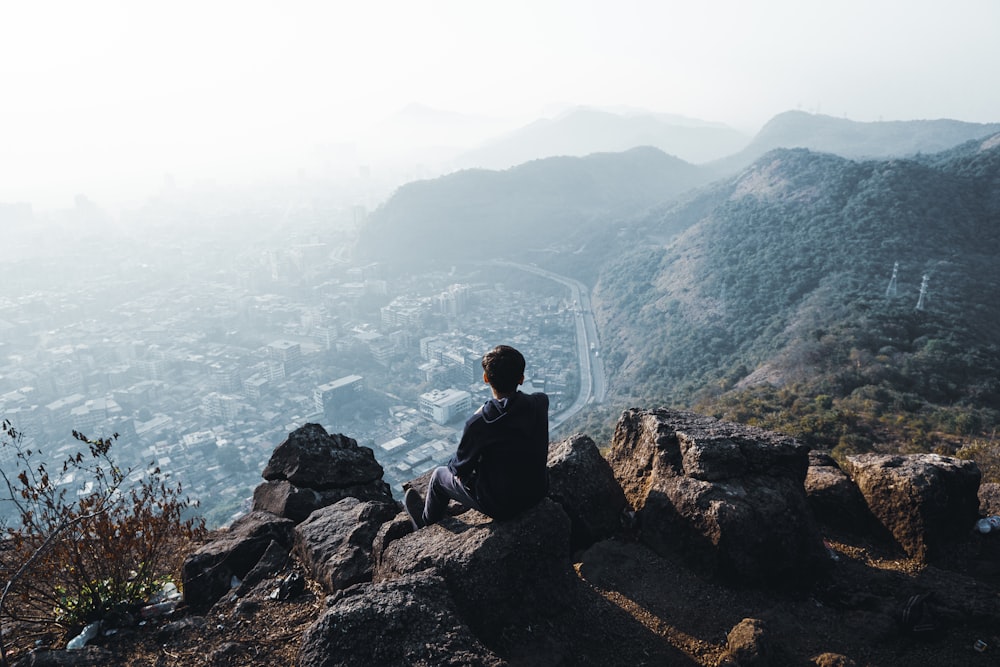 a person sitting on a rock overlooking a city