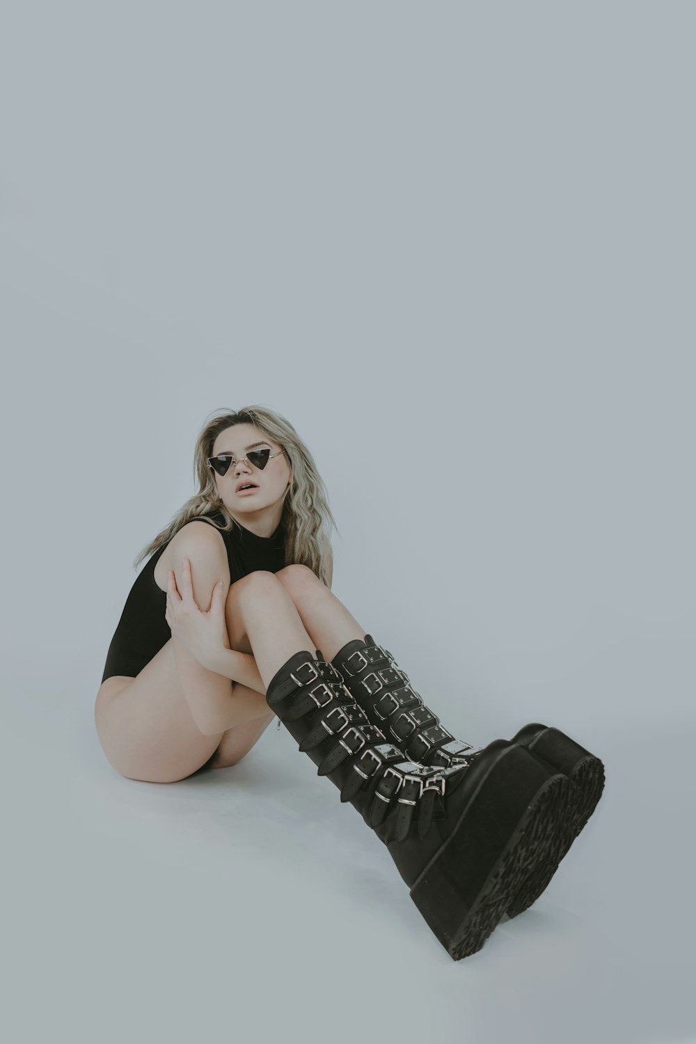 a woman sitting on the ground wearing black boots