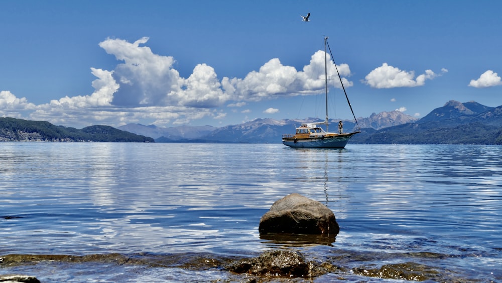 a sailboat in the middle of a lake with mountains in the background