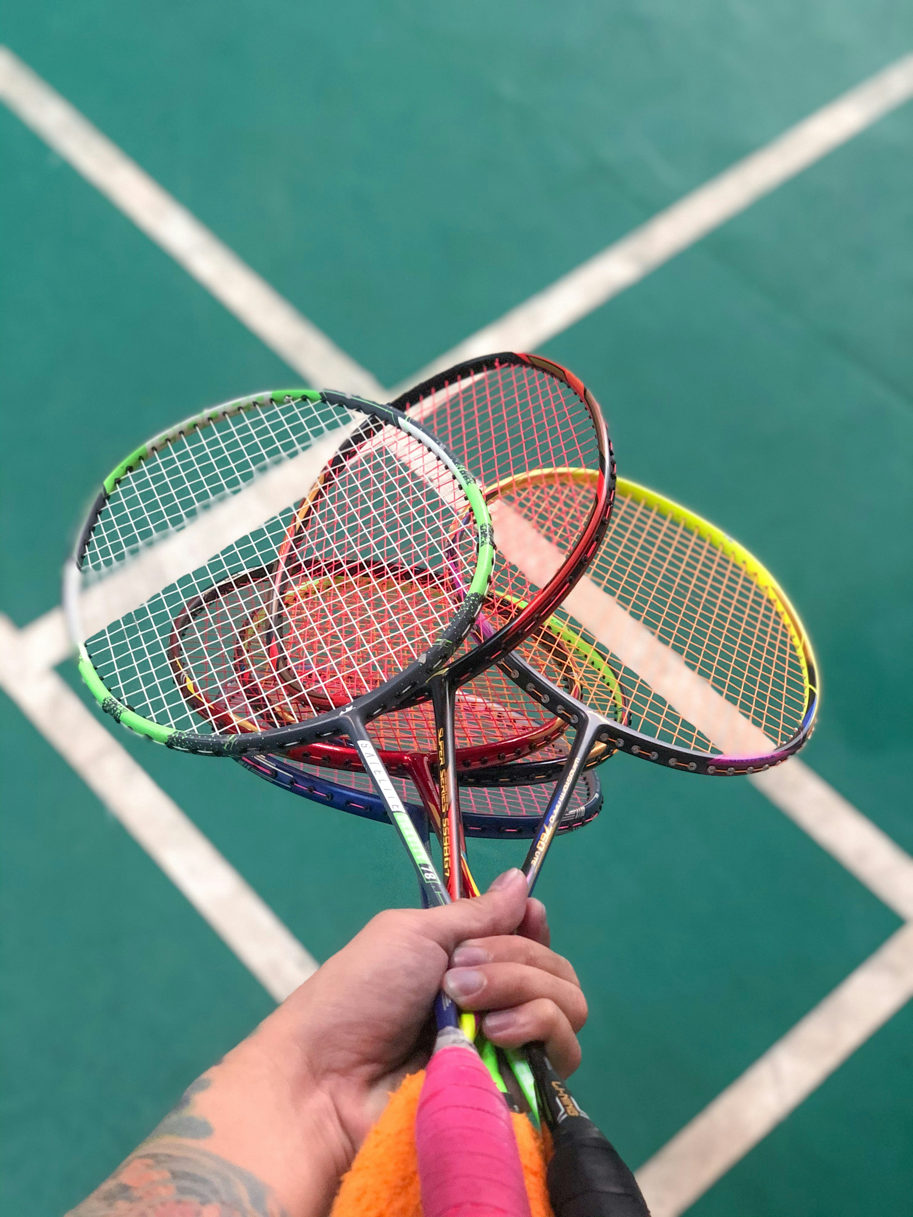 a person holding three tennis rackets on a tennis court