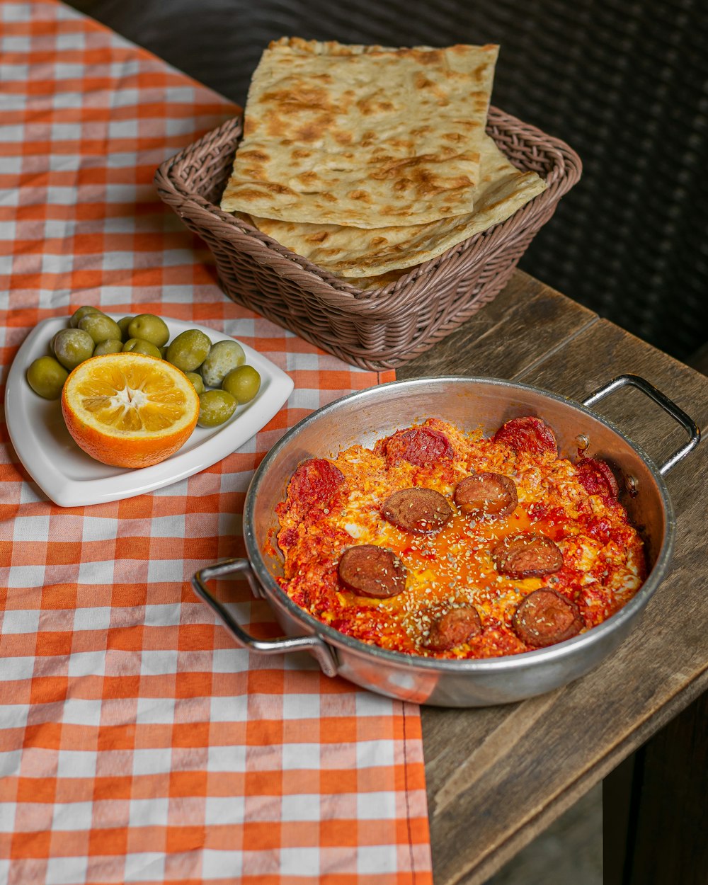 a table topped with a pan of pizza and a bowl of olives