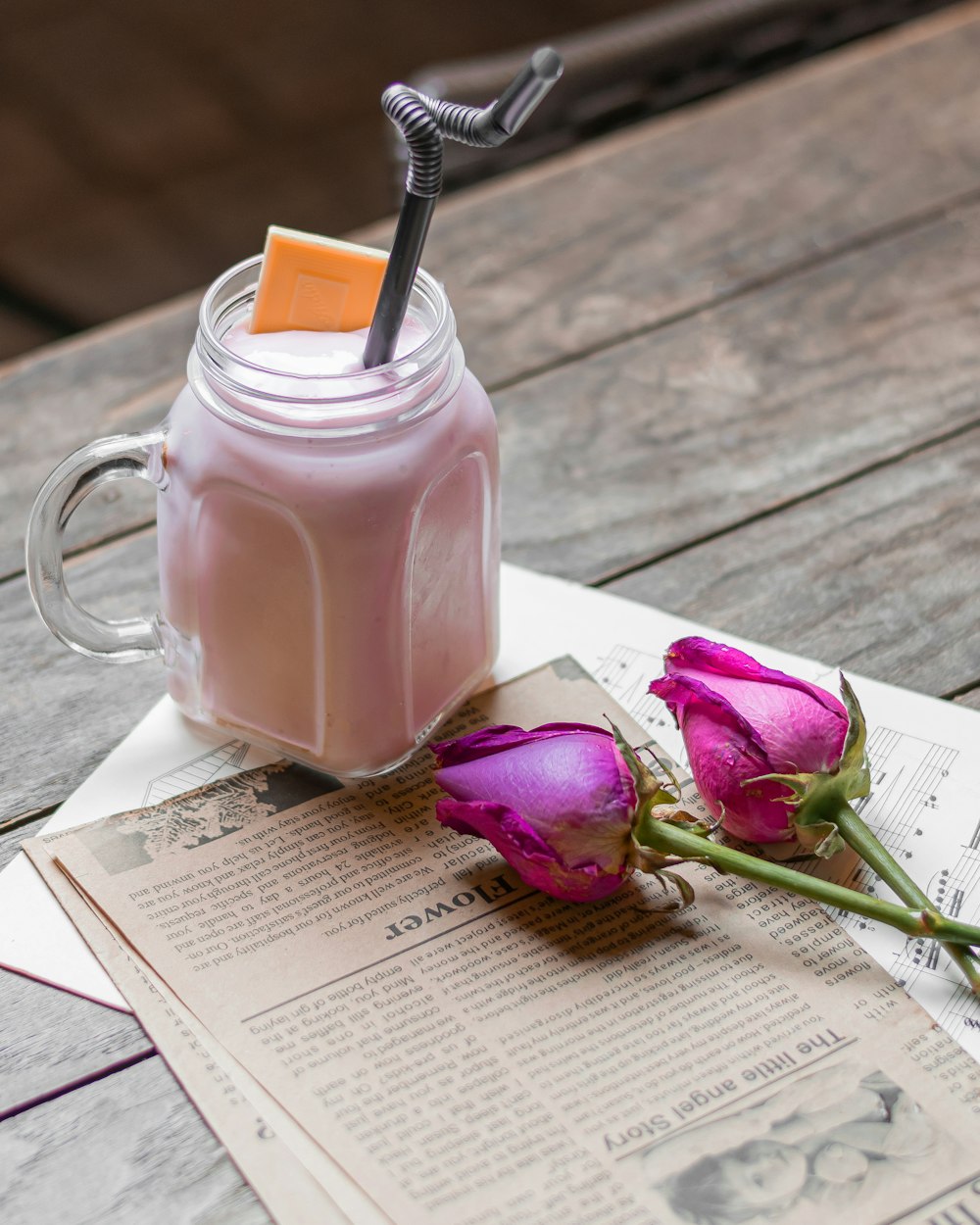 uma bebida rosa com um canudo em um frasco de pedreiro