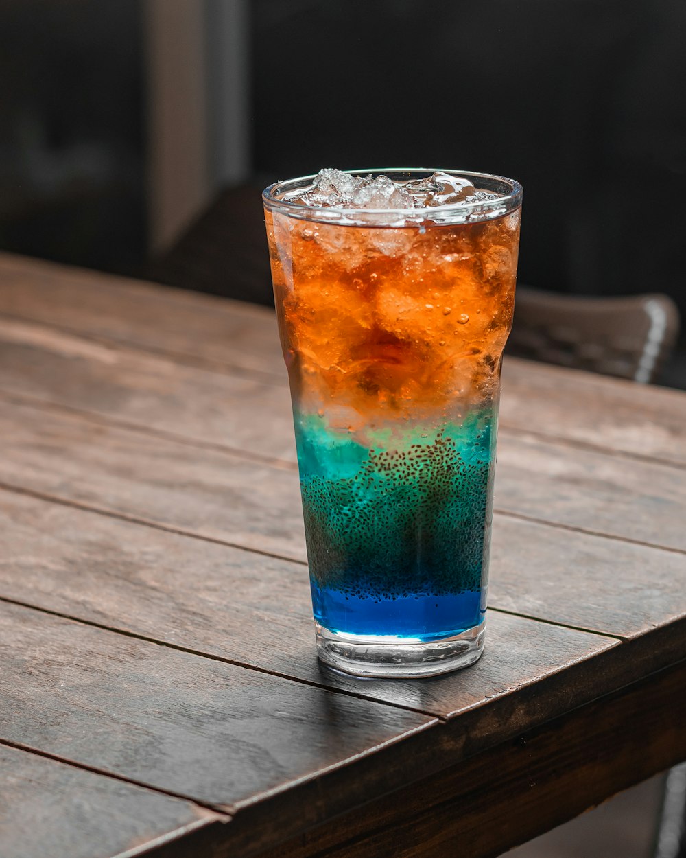 a glass of soda sitting on top of a wooden table