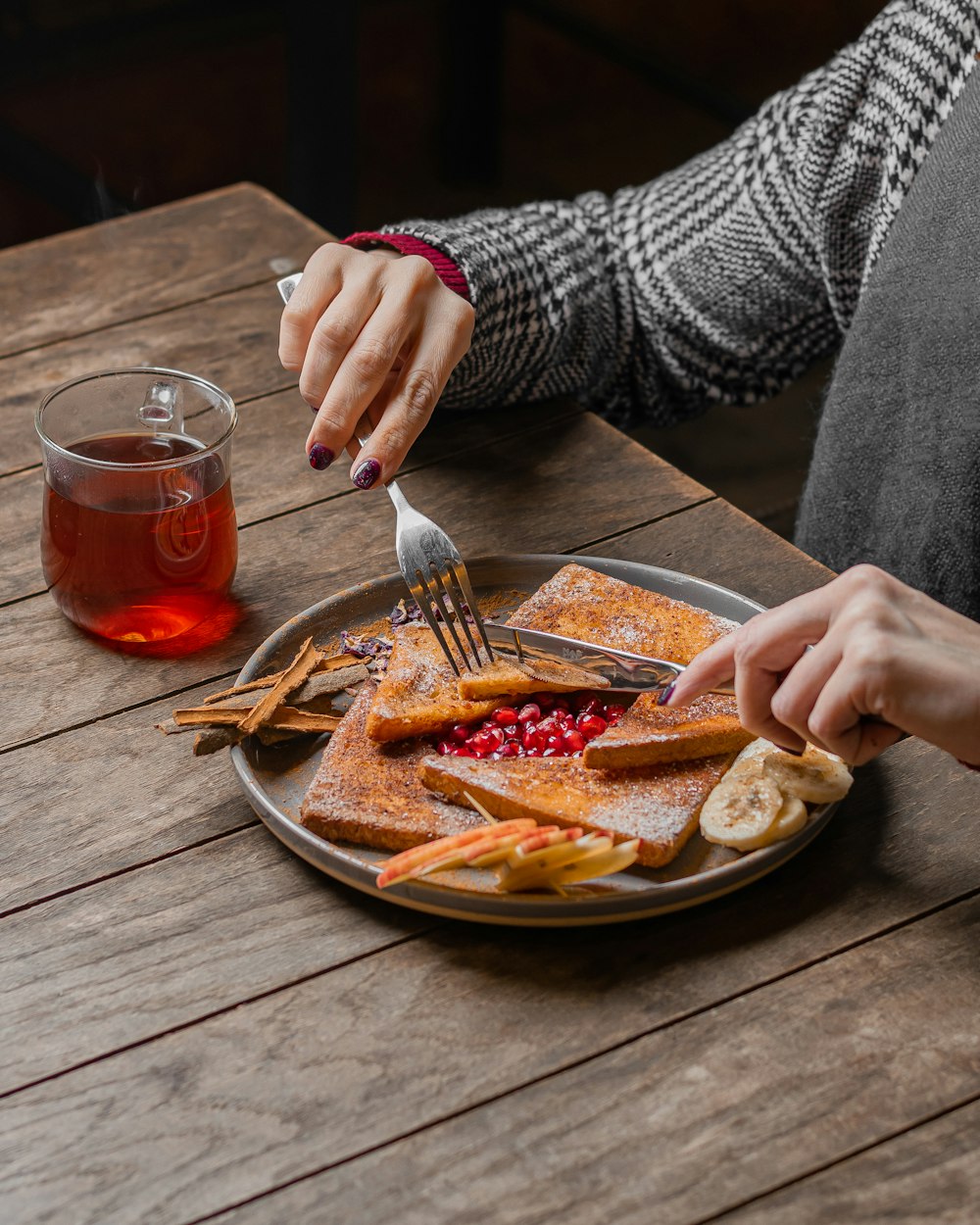 a woman is eating a plate of pancakes with fruit