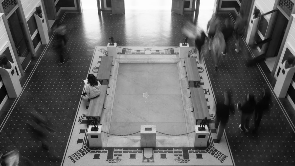 a black and white photo of people walking around a building