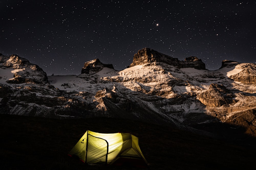 a tent pitched up in the mountains at night