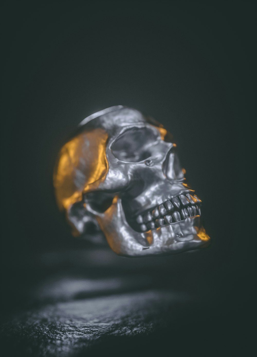 a silver and gold skull ring on a black surface