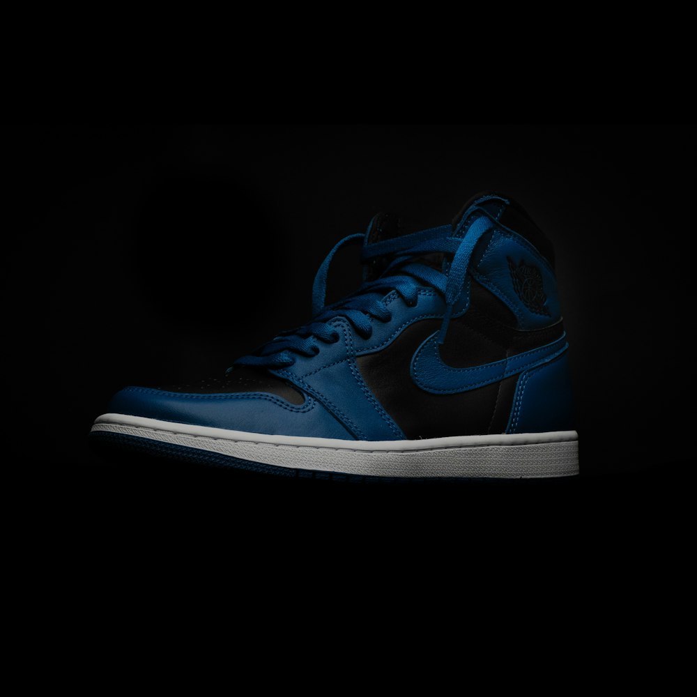 a pair of blue and black sneakers on a black background