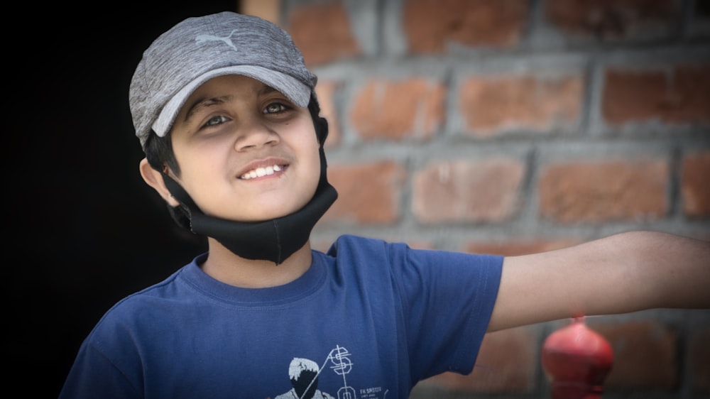 a young boy wearing a helmet and holding a fire hydrant