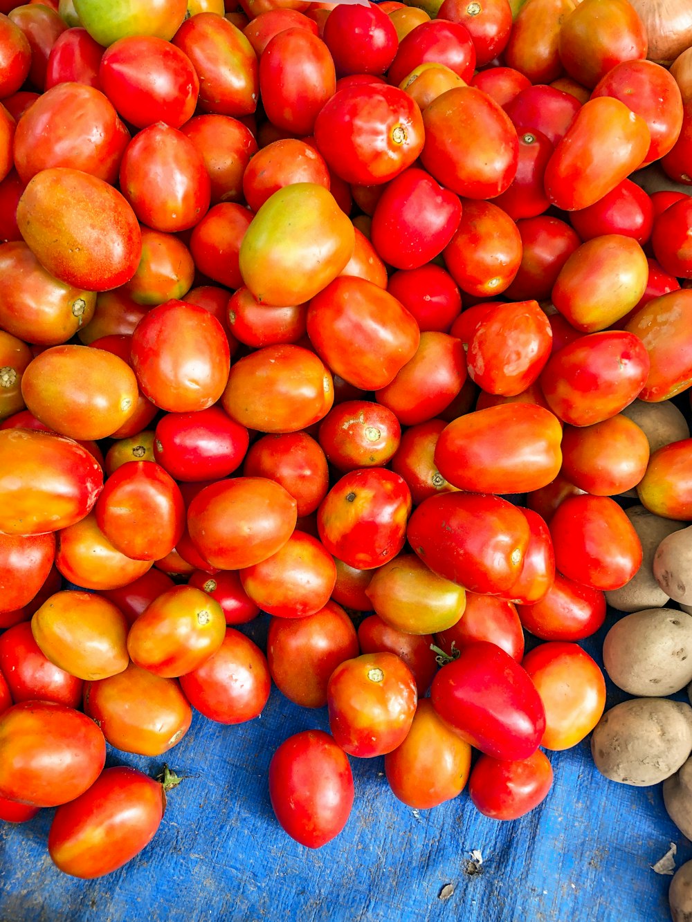 a pile of tomatoes and potatoes on a table