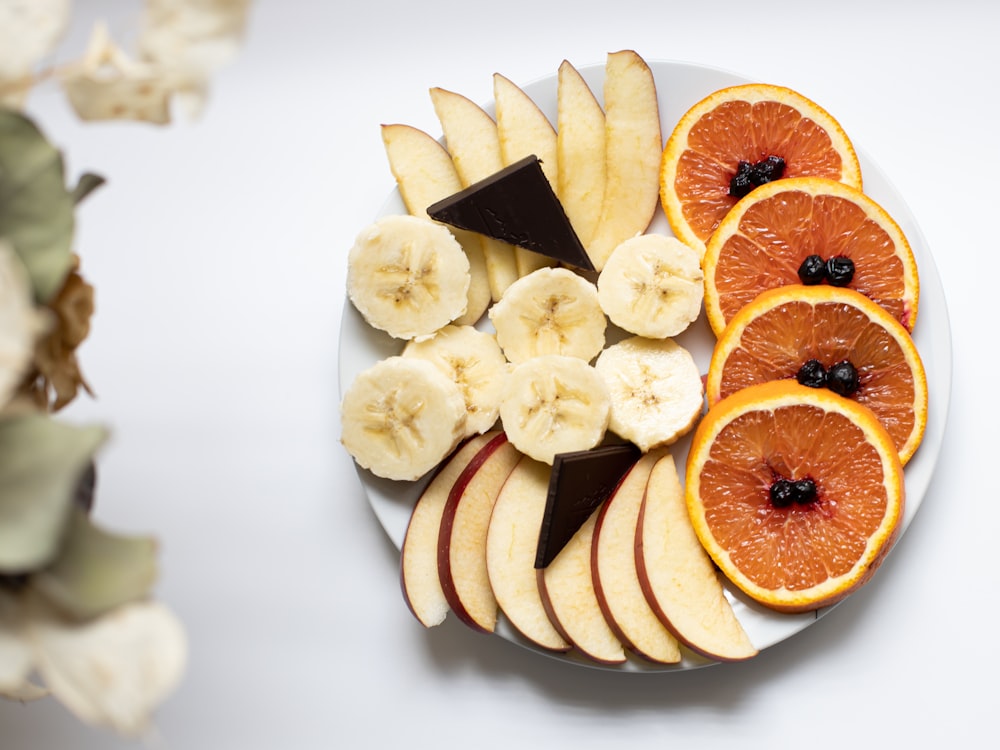 a white plate topped with sliced oranges and bananas