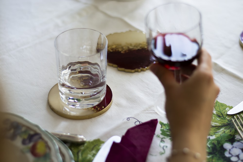 a person holding a glass of wine on a table