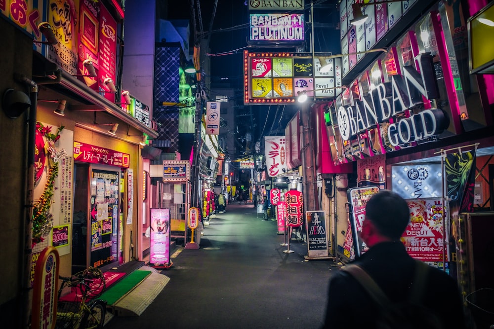 a man walking down a street filled with neon signs