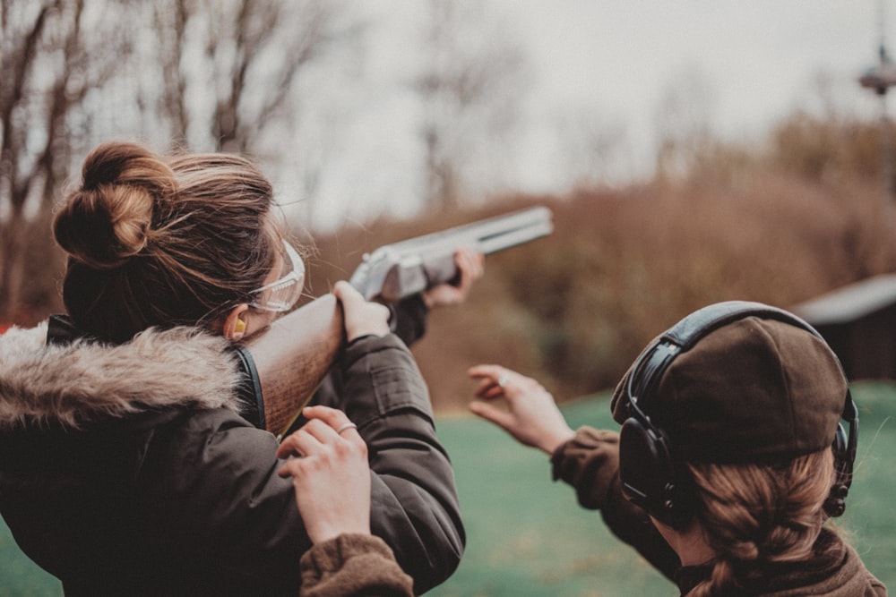 two women are aiming a gun at a target