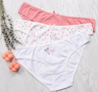 three women's underwear on a white wooden surface