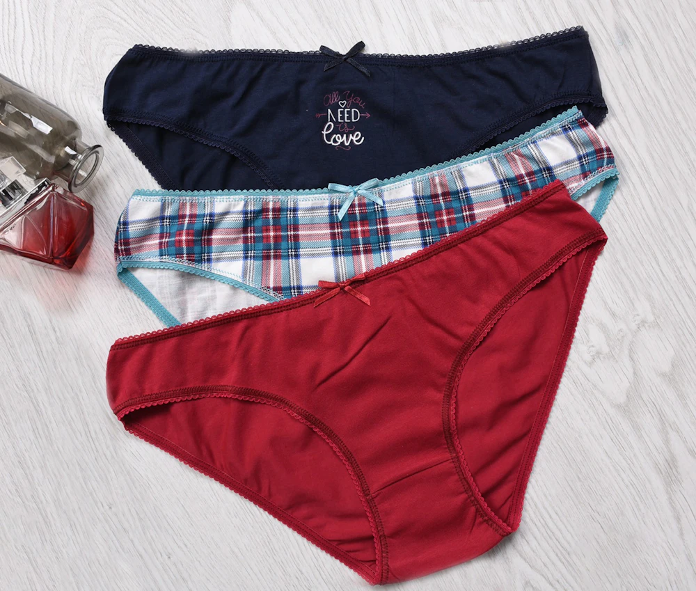 Three pairs of cotton underwear laid out on a light wood surface
